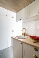 Small modern kitchen units with view of wall of built-in cupboards