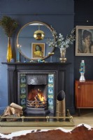 Living room with black fireplace, round mirror, retro artwork and navy painted walls.