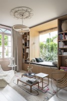 Large window seat built-in to bookshelves overlooking garden