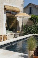 Parasol over small seating area between house and swimming pool
