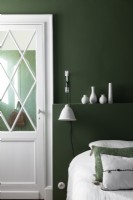 Modern green and white bedroom with display of white ceramics 