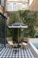 Wicker chairs and black and white parasol by pool 