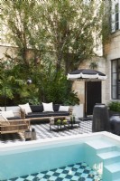 Seating area and swimming pool in couryard with checked paving