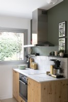 Wooden kitchen unit and cooker against dark green painted wall