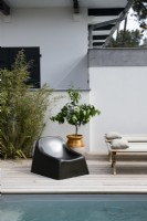 Modern black plastic chair on decking next to swimming pool