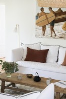 Coastal painting of surfers over sofa in living room