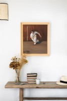 Painting above rustic wooden table in white painted hallway - detail