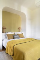 Yellow feature wall in arched alcove around head of bed