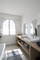 Arched mirrors over twin sinks in bathroom with arched windows