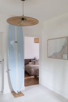 Surfboard propped up in white painted hallway