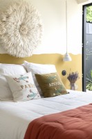 Embroidered pillows and fabric artwork in modern bedroom