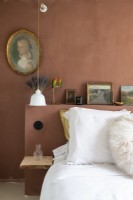 Brown painted wall and headboard with vintage portrait in bedroom