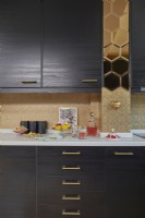 Kitchen detail showing dark brown cabinets, gold mirror tiles and gold painted textured wallpaper.
