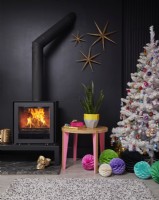 Open plan living room detail showing a decorated Christmas tree, a wood burner stove, painted black walls with gold wall stars.