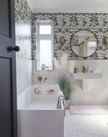 Bathroom with patterned wallpaper, round mirror and gold tap details.