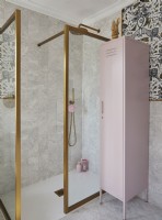 Bathroom with patterned wallpaper, gold frame shower cubicle and a pink storage locker.