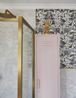 Bathroom detail with patterned wallpaper, gold frame shower cubicle and a pink storage locker.