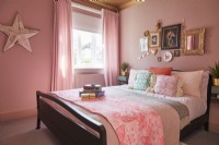 Bedroom with double bed, pink painted walls with framed pictures and a star decoration.