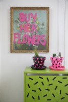 Entrance hall detail with 'Buy her flowers' print, washi tape decorated plant pots and cupboard.