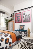 Bedroom with a black faux panelling effect (using black washi tape), framed artwork, animal print bedding, rug and storage seat.