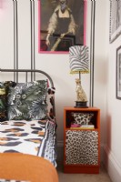 Bedroom detail with a black faux panelling effect (using black washi tape), framed artwork, animal print bedding and an upcycled orange bedside table.