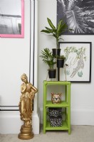 Bedroom detail with a black faux panelling effect (using black washi tape), framed artwork, green shelving with plants and a gold statue.