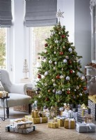 Christmas tree in. living room with gold and silver wrapped gifts