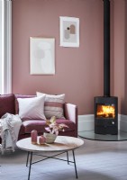 Pink living room with pictures on wall and wood burning stove