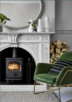 Wood burning stove in grand fireplace with green chair