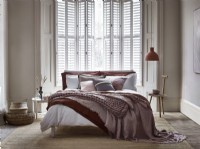 Relaxed modern bedroom with white shutters cracked open