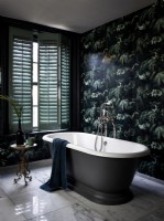 Luxurious bathroom with patterned wallpaper and green shutters