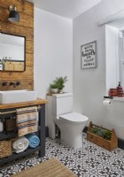 Bathroom with wooden panelling behind the double sinks, storage unit with towel rails and monochrome floor tiles.