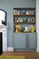 Detail of open shelving for crockery and appliances in an open plan kitchen-diner.