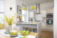 Open plan kitchen-diner with breakfast bar and yellow pendant lights.