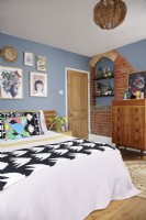 Bedroom with original exposed brickwork, blue painted walls and retro furniture.