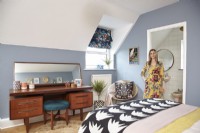 Bedroom with an ensuite bathroom, blue painted walls and mid-century furniture. 