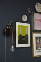 Living room detail showing a gallery wall, an unusual light hanging on navy painted walls.