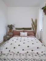 Spare bedroom with pink and green bedding, a throw and white walls.