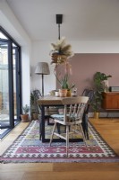 Dining area in an open plan living space with pink colour blocking and vintage furniture.