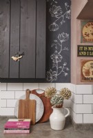 Kitchen details with black painted cupboards, floral artwork and vintage signs.