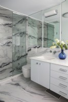 Modern white bathroom with marble patterned flooring and walls.