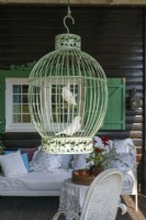 Birds in a green cage hanging in front of the house