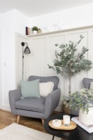 Chair and faux olive tree in the corner of a panelled living room
