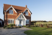 Modern brick new build house with clapperboard porch and paved driveway