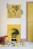 Yellow painted Victorian fireplace in a child's bedroom with vinyl covered hearth and stenciled wall artwork