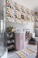 Pink vanity unit in a grey tiled and wallpapered bathroom
