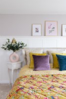 Detail of bed and bedside table in front of white panelled wall


