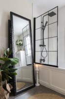 Panelled bath and black shower fixtures with black glazed screen


