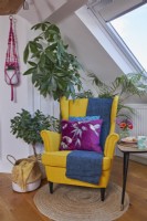 Attic living room detail showing a mid century style yellow armchair, coffee table and plants.