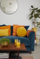 Living room detail with teal blue sofa, orange and yellow cushions and a retro coffee table.